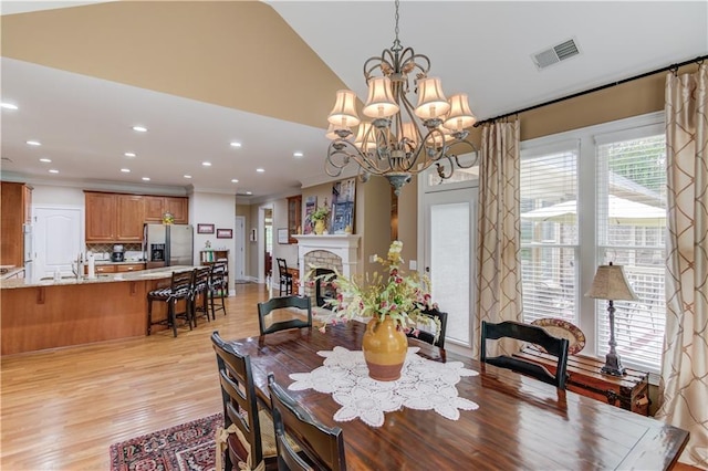 dining area featuring recessed lighting, a fireplace, visible vents, vaulted ceiling, and light wood finished floors