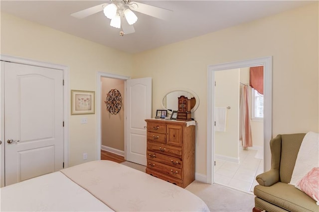 bedroom featuring connected bathroom, light carpet, a ceiling fan, baseboards, and a closet