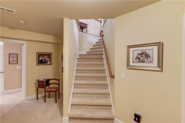 staircase with carpet floors, visible vents, and baseboards