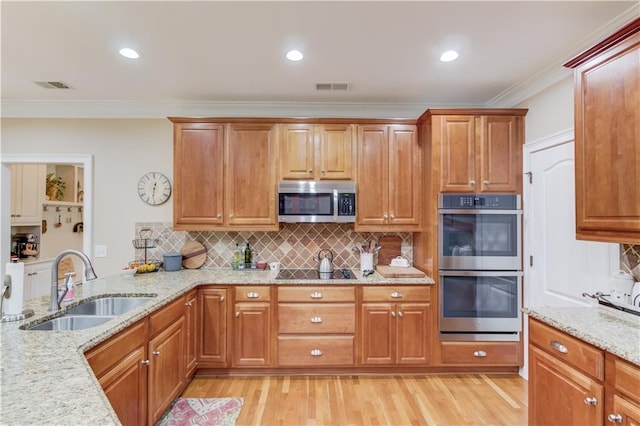 kitchen with light wood-style flooring, stainless steel appliances, a sink, visible vents, and light stone countertops