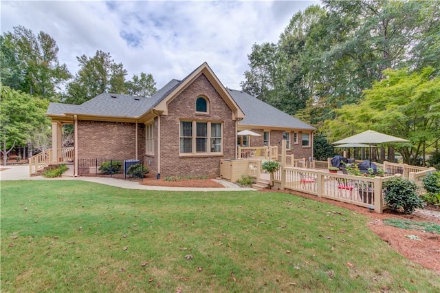 view of front of property with brick siding, a wooden deck, and a front yard