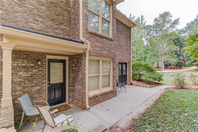 entrance to property with brick siding and a patio area