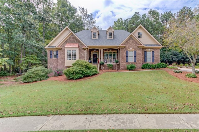 view of front of property with covered porch, a front lawn, and brick siding