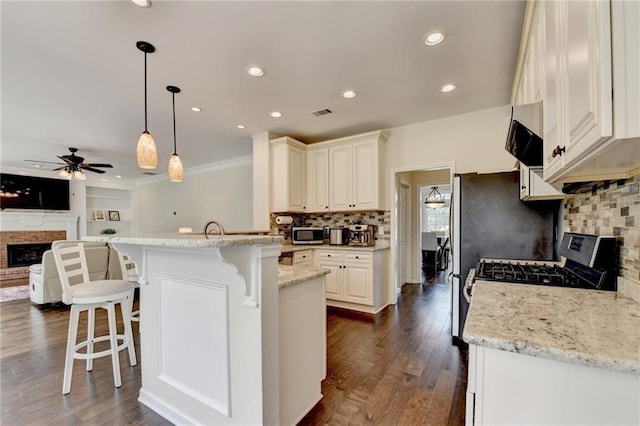 189 Azalea Chase Dr, Suwanee, GA 30024 - kitchen with a fireplace with raised hearth, a kitchen breakfast bar, appliances with stainless steel finishes, open floor plan, and ceiling fan