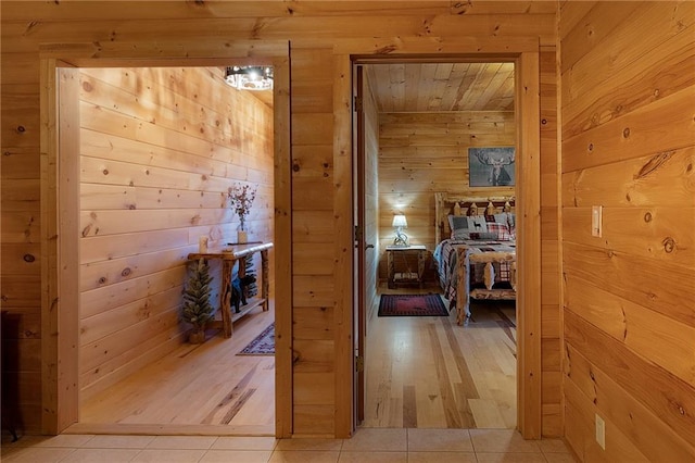 hallway with light tile patterned floors and wooden walls