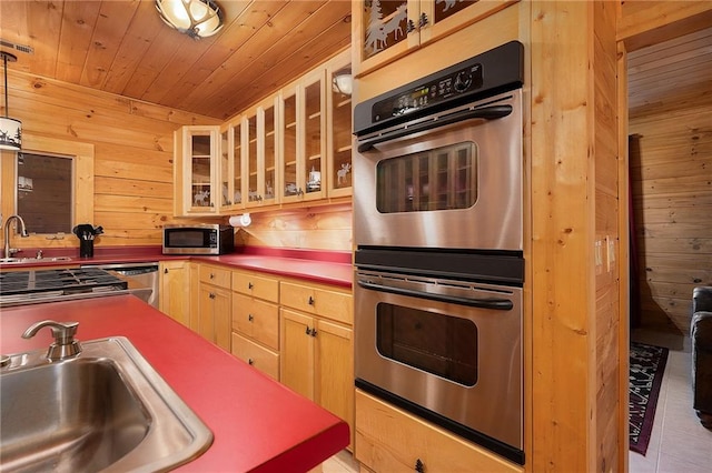 kitchen featuring stainless steel appliances, wooden ceiling, wooden walls, and sink