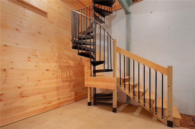 staircase featuring concrete flooring and wood walls