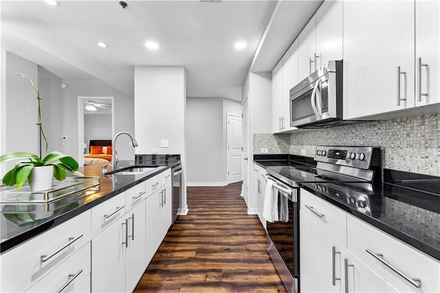 kitchen featuring backsplash, appliances with stainless steel finishes, white cabinets, and a sink