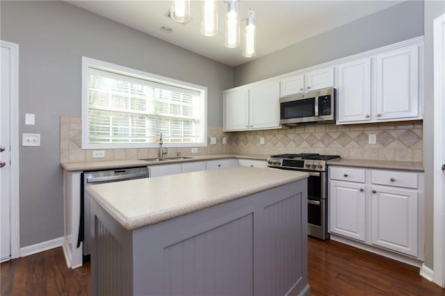 kitchen with tasteful backsplash, appliances with stainless steel finishes, white cabinetry, a kitchen island, and a sink