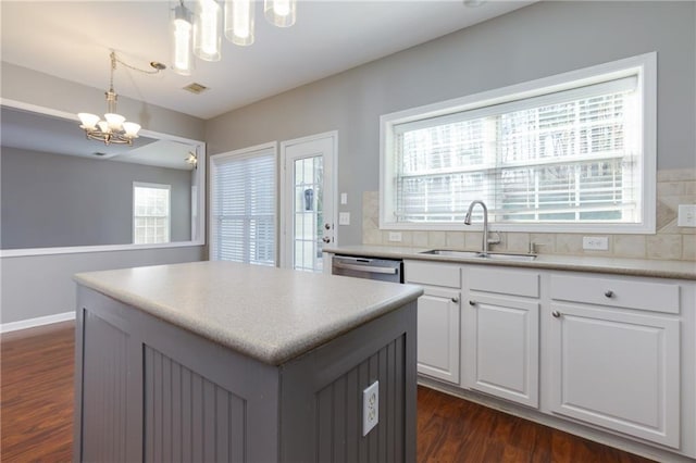 kitchen featuring dark wood-style floors, a notable chandelier, white cabinetry, a kitchen island, and a sink