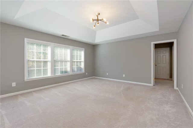 unfurnished room with a chandelier, light carpet, visible vents, baseboards, and a tray ceiling