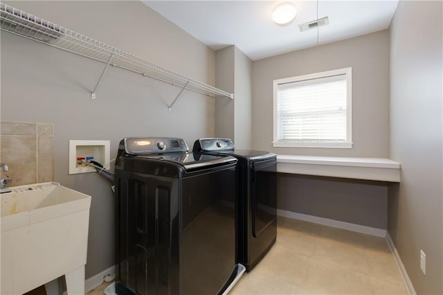 clothes washing area featuring laundry area, a sink, visible vents, baseboards, and washer and clothes dryer