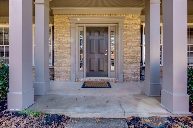 property entrance featuring brick siding and a porch