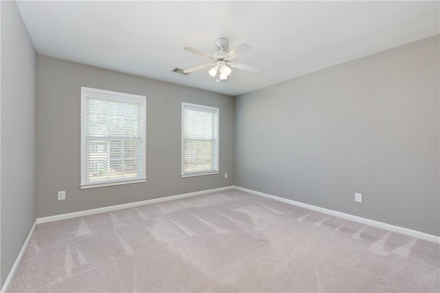 spare room featuring light carpet, ceiling fan, visible vents, and baseboards