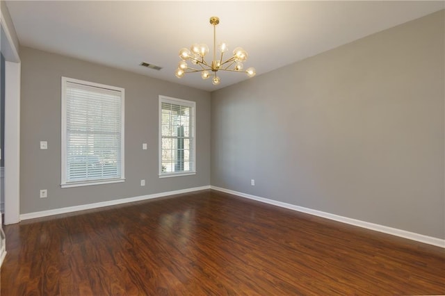 spare room featuring baseboards, visible vents, dark wood-style flooring, and a notable chandelier