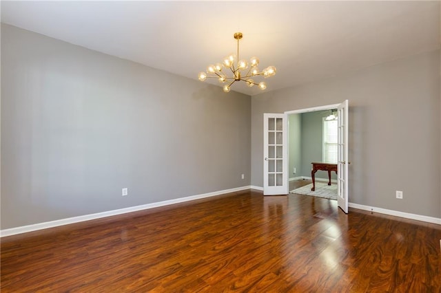 spare room with an inviting chandelier, french doors, baseboards, and wood finished floors