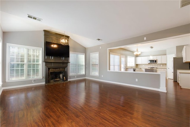 unfurnished living room with a chandelier, lofted ceiling, visible vents, and a fireplace