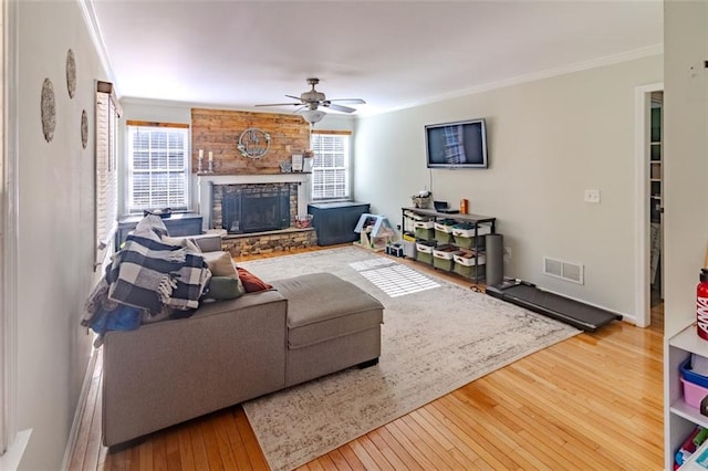 living room with wood-type flooring, a healthy amount of sunlight, a fireplace, and crown molding