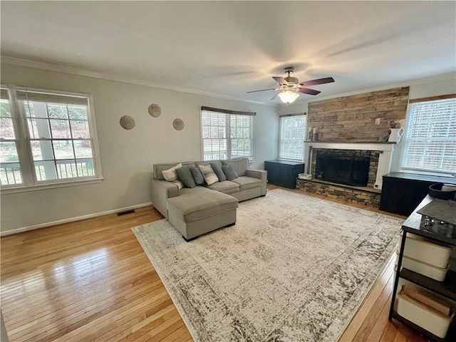 living area with hardwood / wood-style flooring, a fireplace, visible vents, and crown molding