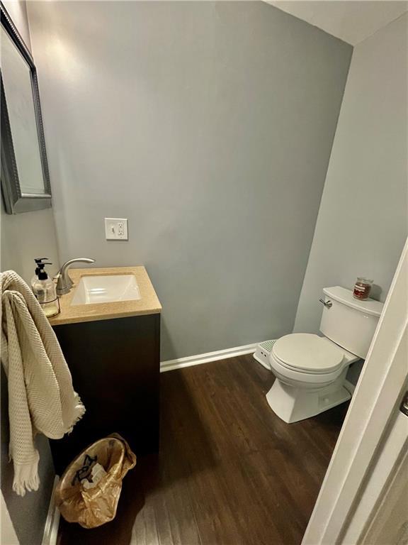 bathroom with toilet, baseboards, wood finished floors, and vanity