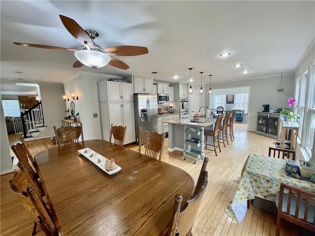 dining space with recessed lighting, crown molding, light wood-style flooring, and stairs