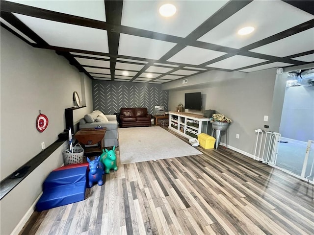 interior space featuring an accent wall, coffered ceiling, baseboards, and wood finished floors