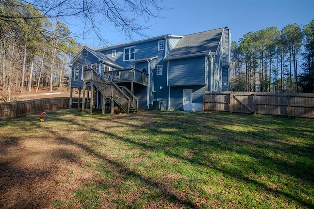 rear view of house featuring stairs, a lawn, a wooden deck, and a fenced backyard