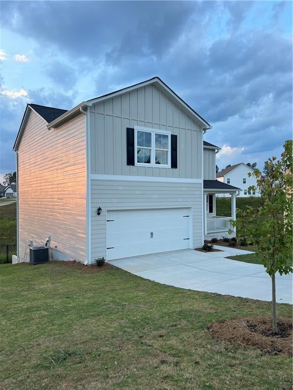 exterior space featuring a lawn, a garage, and central air condition unit