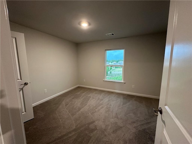 spare room featuring dark colored carpet