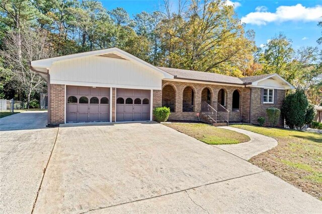 single story home featuring a front lawn, a porch, and a garage