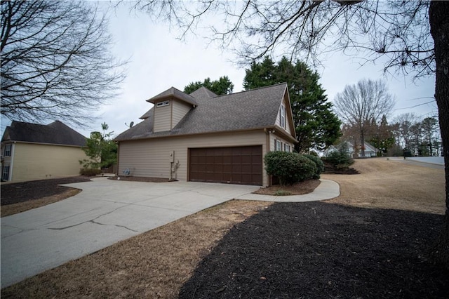 view of side of home with concrete driveway and roof with shingles