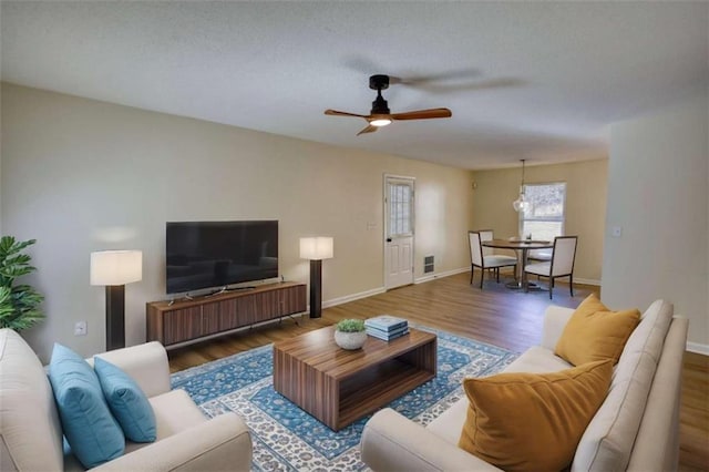 living room featuring a ceiling fan, baseboards, and wood finished floors