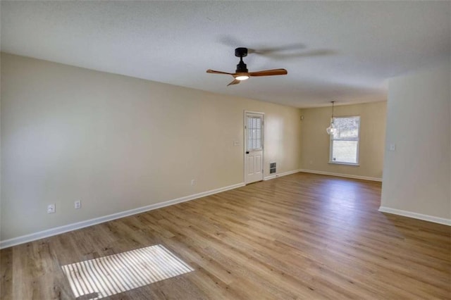 spare room with light wood finished floors, a ceiling fan, and baseboards