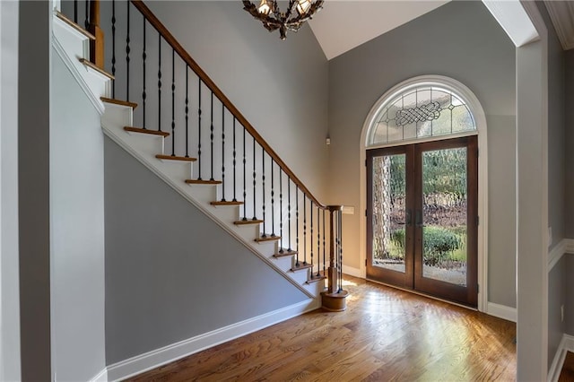 entrance foyer with french doors, a notable chandelier, and wood-type flooring