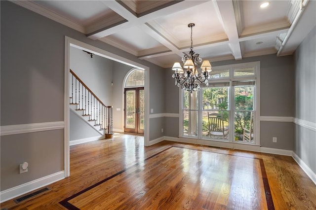 empty room with beamed ceiling, plenty of natural light, coffered ceiling, and hardwood / wood-style floors