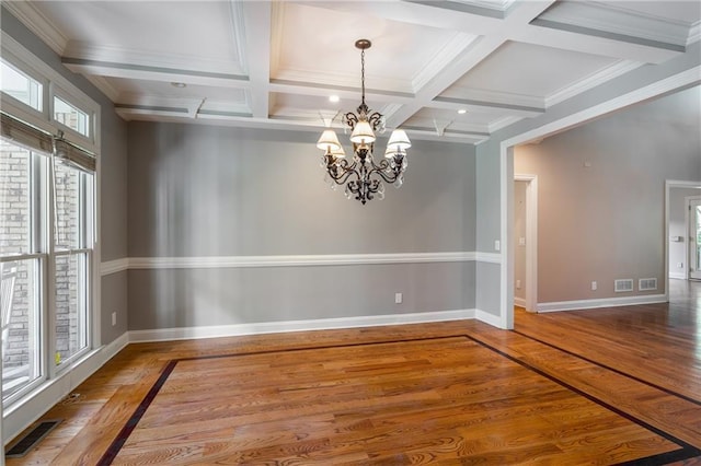 empty room featuring coffered ceiling, beamed ceiling, ornamental molding, a notable chandelier, and hardwood / wood-style flooring