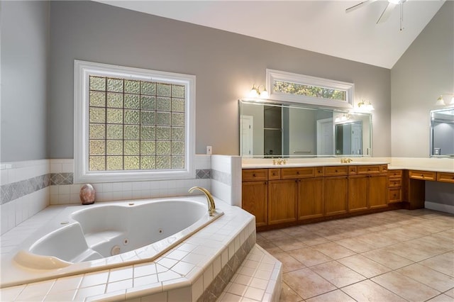 bathroom with lofted ceiling, vanity, ceiling fan, tile patterned floors, and tiled tub