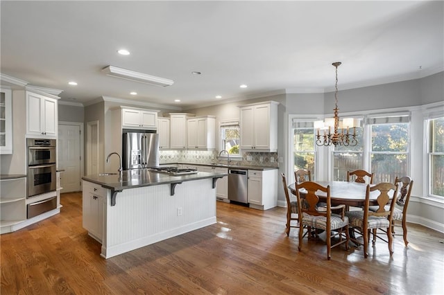 kitchen with a chandelier, appliances with stainless steel finishes, white cabinetry, and a kitchen island