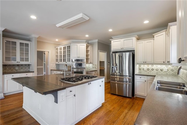 kitchen featuring decorative backsplash, sink, white cabinetry, an island with sink, and stainless steel appliances