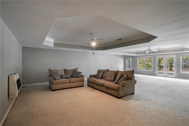 carpeted living room with a raised ceiling, ceiling fan, crown molding, and heating unit