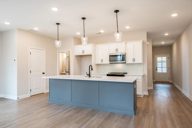 kitchen with pendant lighting, sink, a kitchen island with sink, and white cabinets