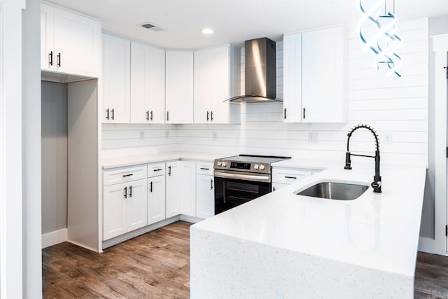 kitchen with wood finished floors, visible vents, stainless steel electric range, a sink, and wall chimney range hood