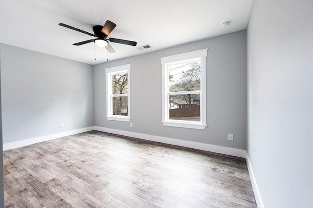 empty room featuring visible vents, ceiling fan, baseboards, and wood finished floors