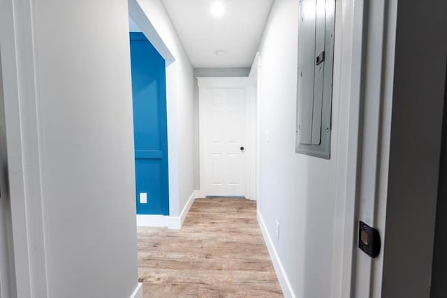 hallway featuring electric panel, light wood-type flooring, and baseboards