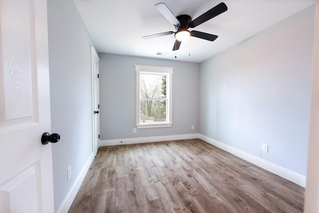 empty room featuring visible vents, ceiling fan, baseboards, and wood finished floors