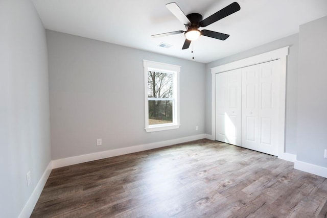 unfurnished bedroom with visible vents, a ceiling fan, wood finished floors, a closet, and baseboards