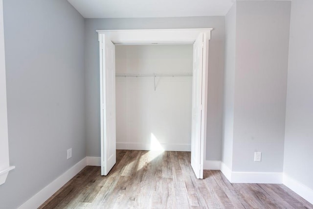 unfurnished bedroom with a closet, baseboards, and wood finished floors