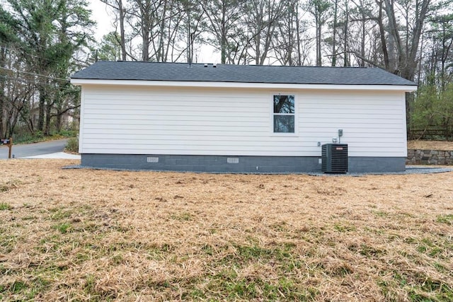 view of property exterior featuring a shingled roof, central AC unit, and crawl space