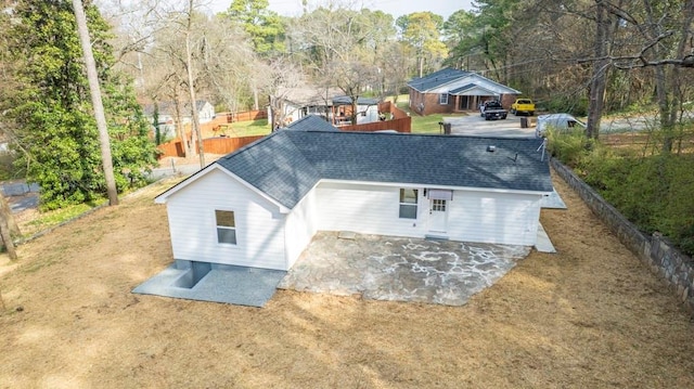 rear view of property with a patio, fence, and roof with shingles