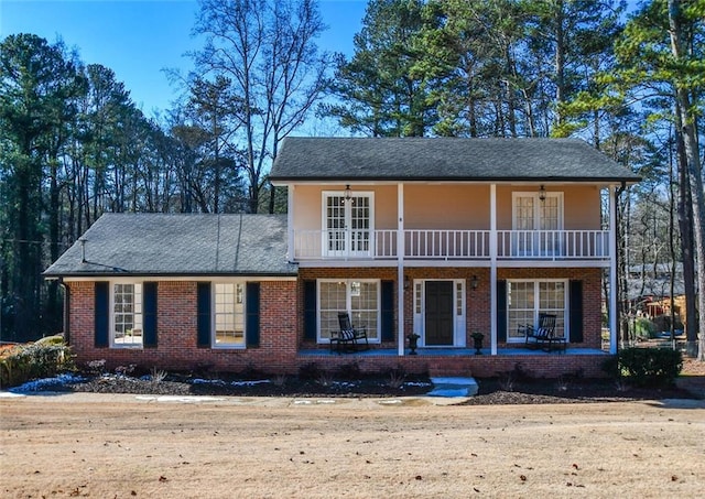 view of front of house featuring brick siding, ceiling fan, a porch, and a balcony